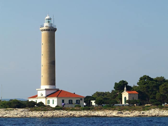 Le phare de Veli Rat avec sa tour blanche et sa maison de gardien jaune sur Dugi Otok